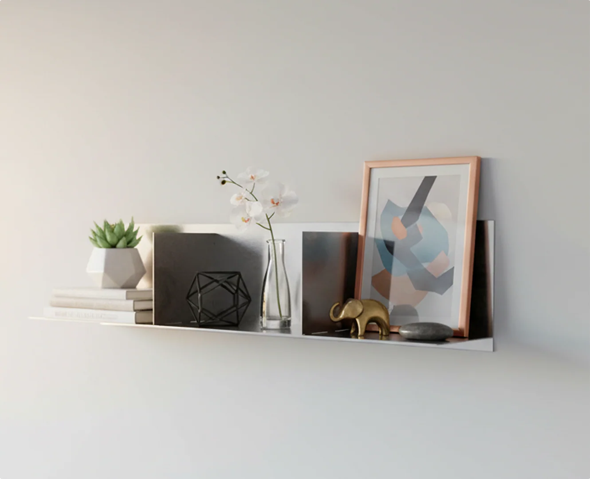 Bespoke stainless steel divider floating shelf by Fig & Forge styled as an architectural gallery for books and minimalist art in a sunlit modern interior