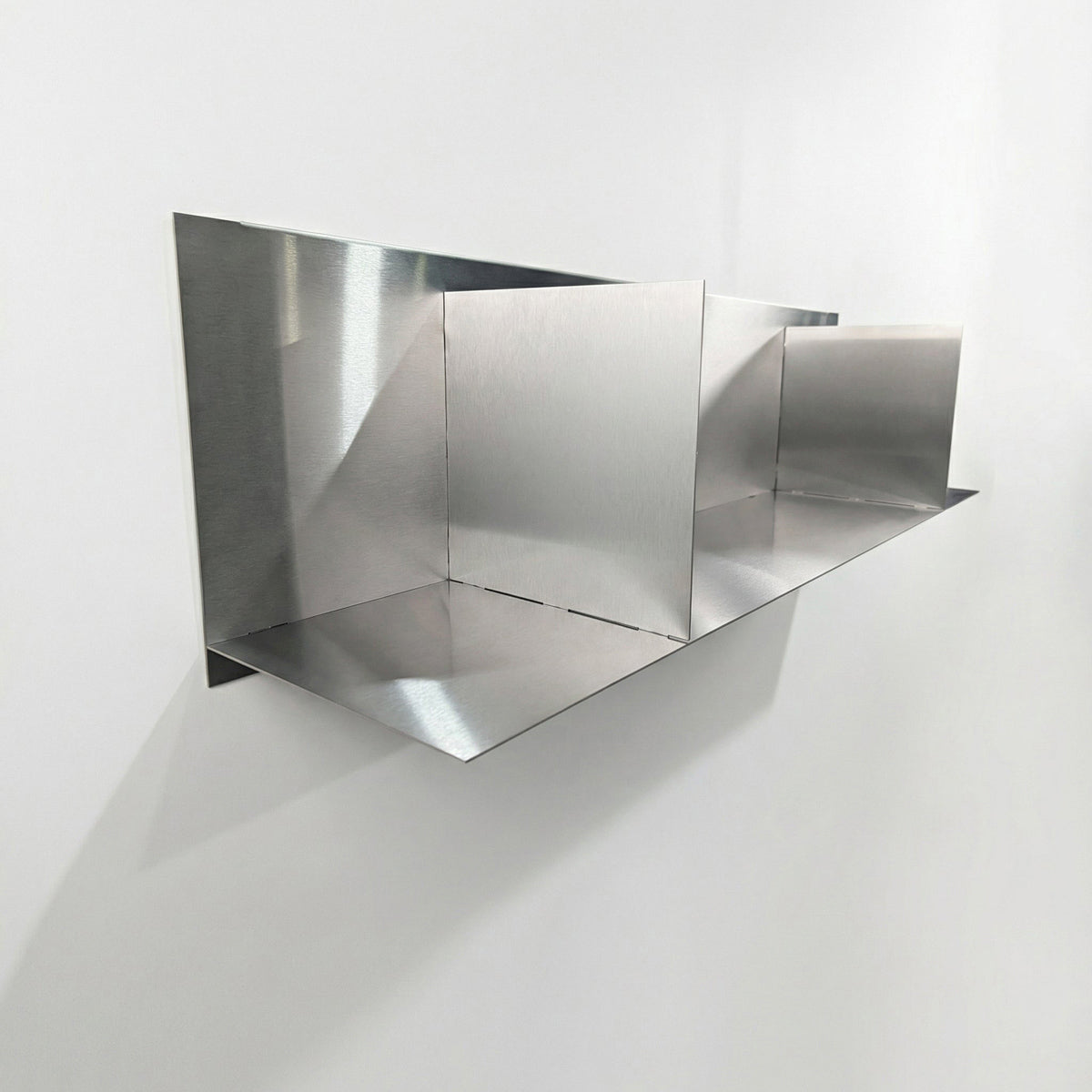 Side-angle view of a heavy-duty stainless steel divider floating shelf by Fig & Forge, highlighting the seamless industrial finish and low-profile wall mounting
