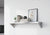 Custom stainless steel Vector shelf by Fig & Forge with angled support gussets, styled as a minimalist bookshelf on a cream color wall