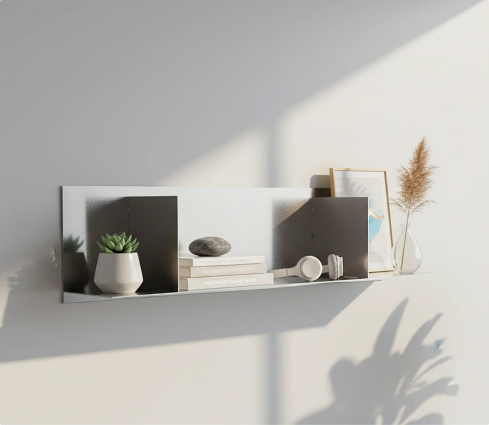 Custom-length stainless steel divider shelf by Fig & Forge mounted on a light grey wall, featuring organized sections for books, headphones, and modern decor