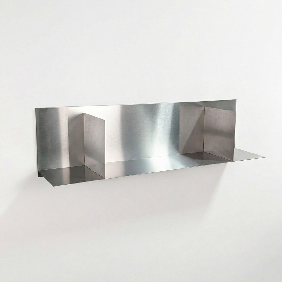Front perspective of a custom-cut brushed stainless steel divider shelf by Fig & Forge, showing the precision-welded vertical partitions for organized wall storage